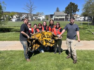 Image of students and staff holding up old sign found during cleanup